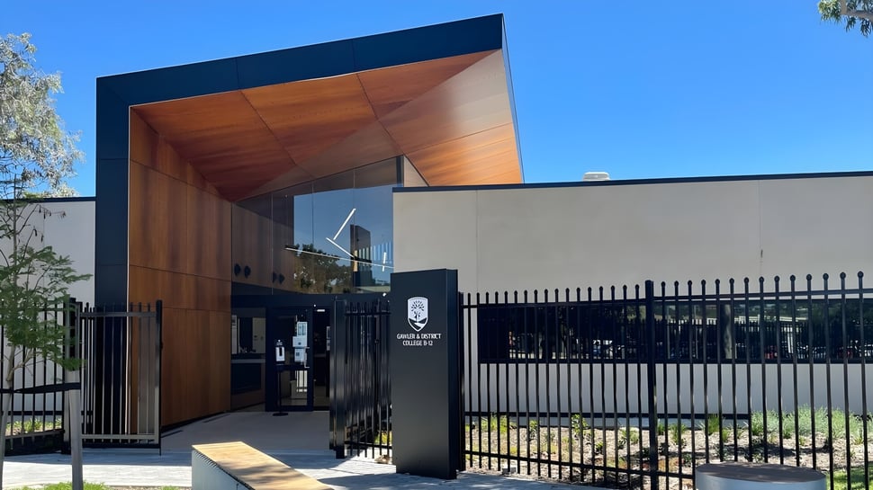 El moderno edificio del Gawler and District College con balcón de madera y cerca de metal bajo un cielo despejado.