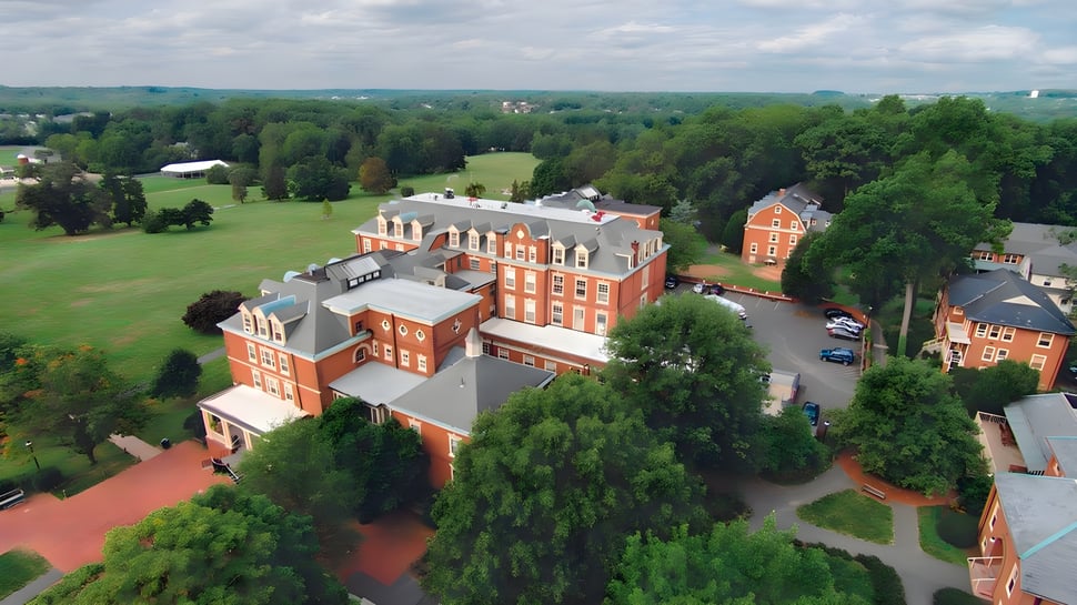 El campus de George School muestra una combinación de edificios históricos y modernos de ladrillo rojo rodeados de un paisaje verde.