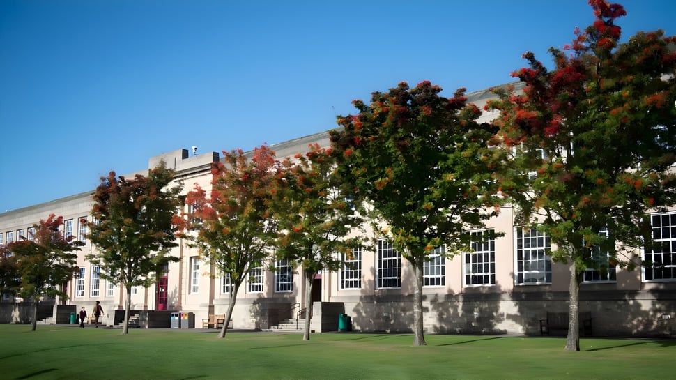 El terreno de George Watson’s College muestra un césped cubierto de hierba y edificios frente a árboles de colores otoñales.