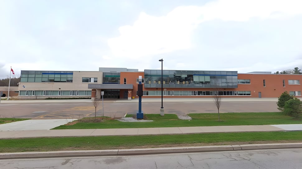 El moderno edificio de varios pisos de la Georgian Bay District Secondary School con paredes de vidrio y un paisaje exterior diseñado.