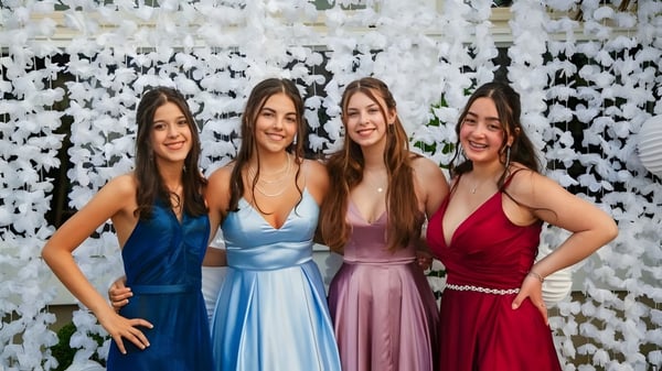Cuatro estudiantes de la Geraldine High School posan juntas frente a una decoración floral.