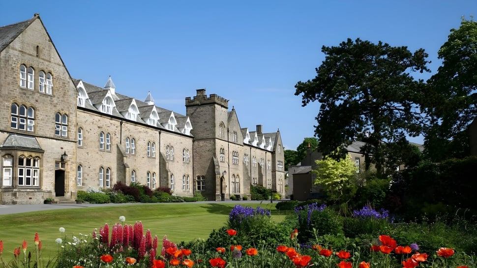 El edificio de estilo medieval de la Giggleswick School está rodeado de un jardín floreciente con una variedad de plantas.