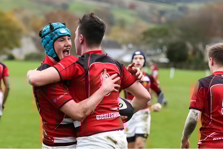 Un grupo de jugadores de rugby de la Giggleswick School celebra en un campo de juego.