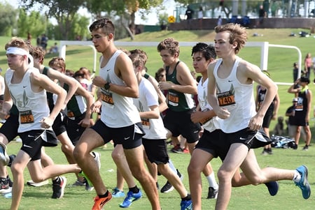 Un grupo de estudiantes masculinos participa en una competencia de carrera en un campo en el campus de Gilbert Christian Schools.