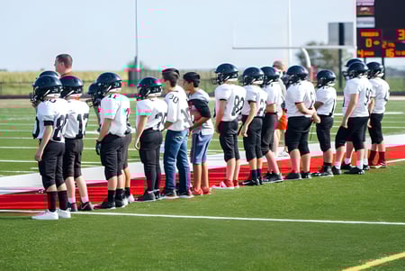 Un grupo de futbolistas en uniforme está en el campo de juego en Gilbert Public Schools frente a un marcador.