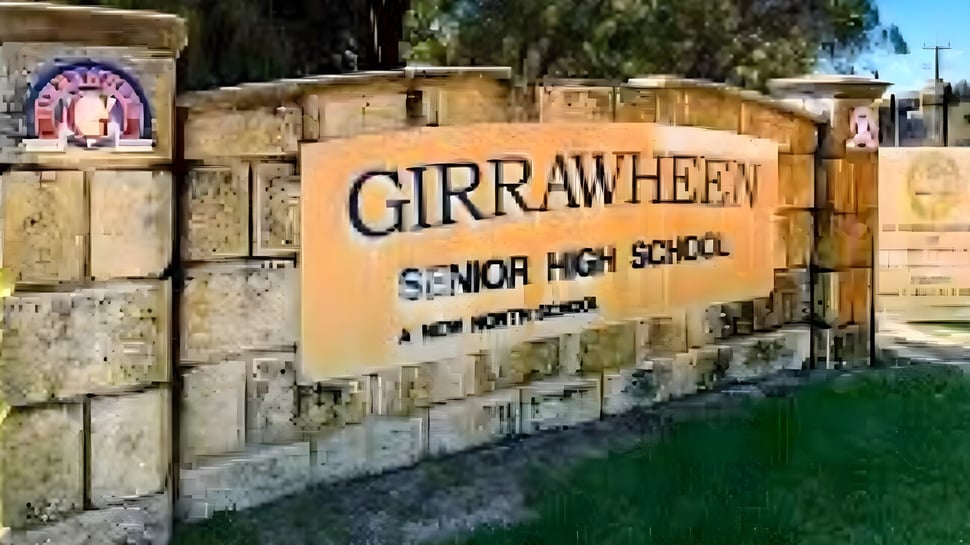 La placa de piedra con la inscripción Girrawheen Senior High School está frente a árboles y edificios en el campus escolar.