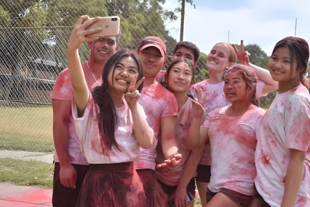 Estudiantes de la Girrawheen Senior High School se toman un selfie afuera con polvo rosa.