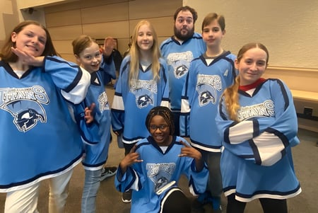 Un grupo de estudiantes de la École secondaire publique Gisèle-Lalonde lleva camisetas azules y posan juntos en el vestuario.