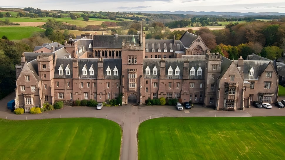 El histórico edificio del castillo del Glenalmond College se encuentra en un amplio paisaje con céspedes y jardines bien cuidados.