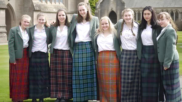 Un grupo de estudiantes en uniforme está frente a un edificio histórico en el campus del Glenalmond College.