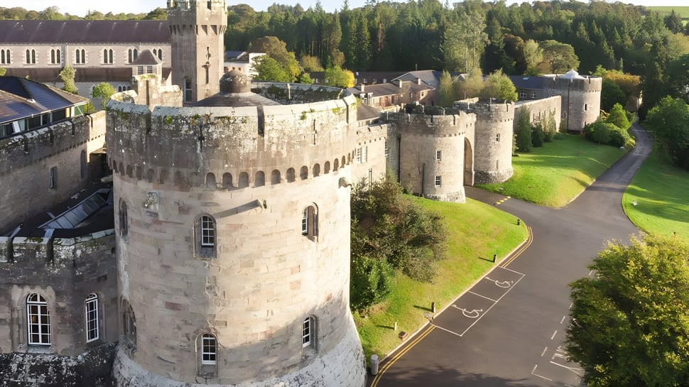 La Glenstal Abbey School muestra un castillo medieval con altas torres de piedra y rodeado de un paisaje verde.