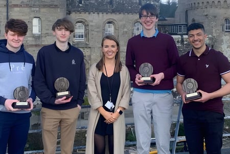 Un grupo de cinco estudiantes está frente a un edificio histórico de la Glenstal Abbey School sosteniendo premios.