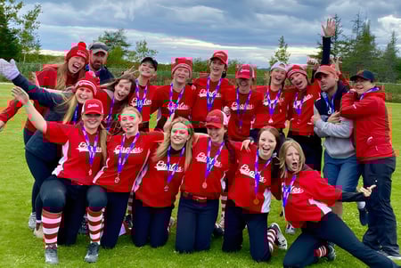 Estudiantes de la Glovertown Academy celebran juntos en un campo bajo un cielo nublado.