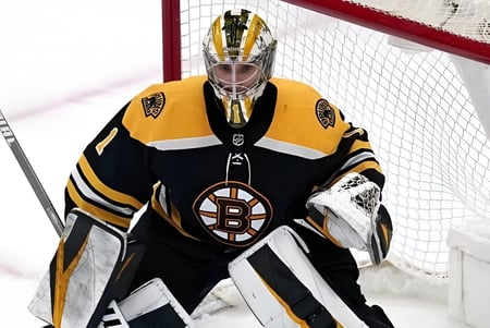 Un portero de hockey con uniforme amarillo y negro está frente a la portería roja en el campo del Goderich District Collegiate Institute.