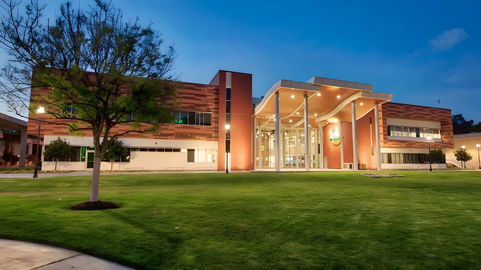 El moderno edificio con fachada de vidrio en el campus del Golden West College está rodeado de césped bien cuidado y árboles.