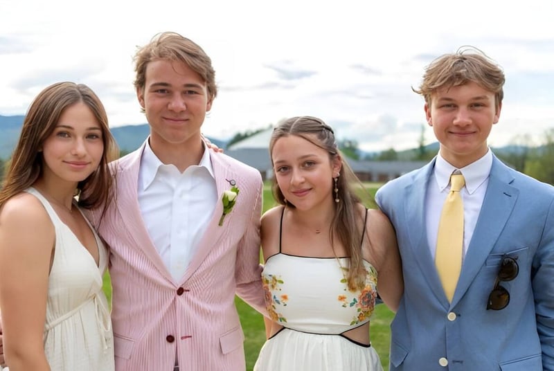Un grupo de cuatro estudiantes de la Gould Academy posan al aire libre frente a montañas y árboles.