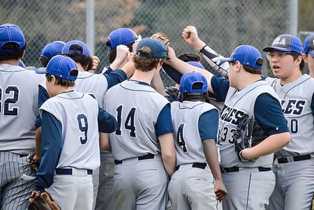 Estudiantes de la Grand River Academy celebran juntos en el campo de béisbol con compañeros de equipo al fondo.