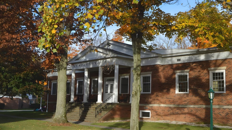 El edificio de ladrillo con porche de columnas se encuentra en el terreno de la Grand River Academy en un entorno otoñal.