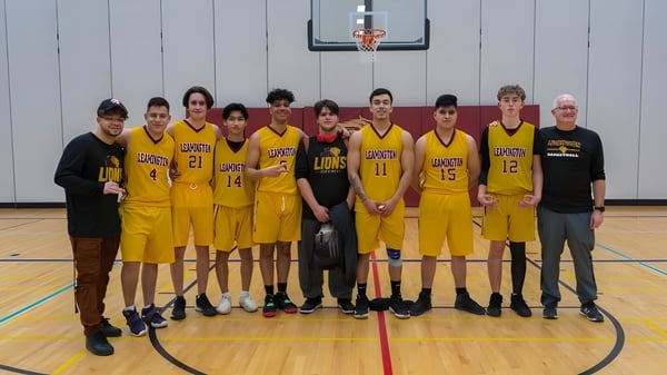 Un grupo de jóvenes jugadores y jugadoras de baloncesto está junto en la cancha de baloncesto del Greater Essex County District School Board.
