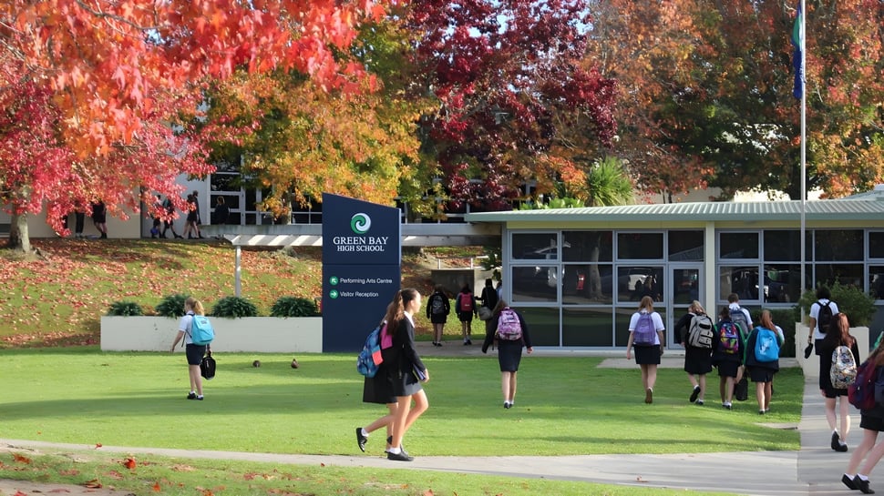 Estudiantes de la Green Bay High School caminan y se reúnen en el campus entre árboles de colores otoñales.