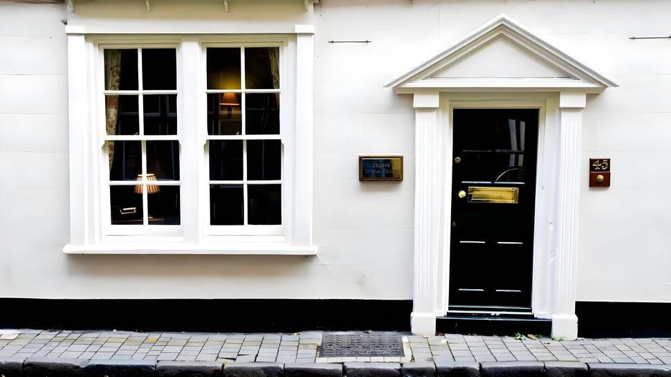 Un edificio blanco con puerta de madera negra y gran ventana en el campus de Greene's College Oxford.