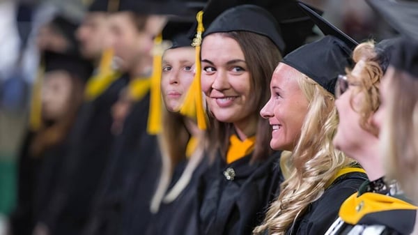 Un grupo de graduados en togas negras y birretes se agrupa durante la ceremonia de graduación del Guelph Collegiate Vocational Institute.