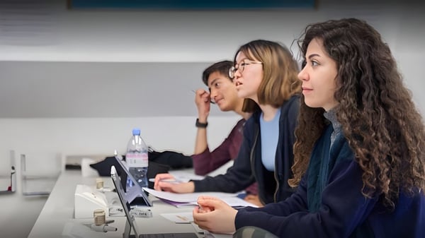 Los estudiantes de la Guildhouse School London están sentados en una mesa y trabajan juntos en el aula.