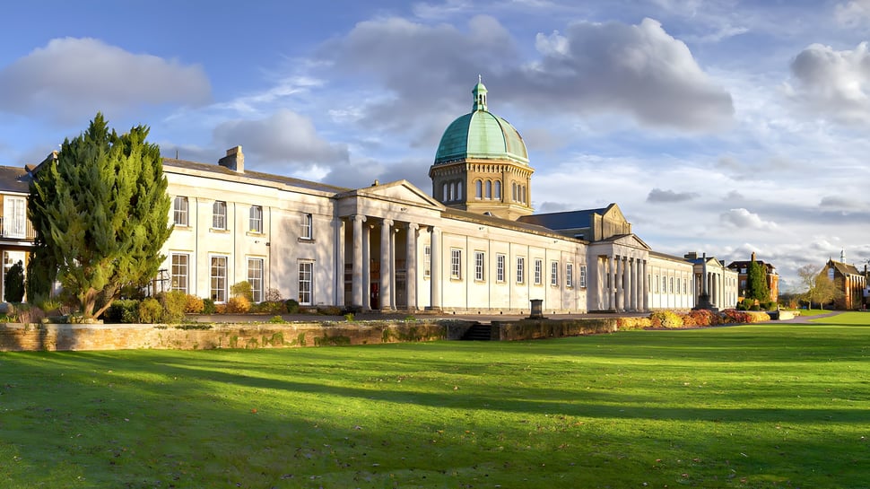 Edificio con cúpula y techo verde en el campus de la Haileybury School frente a un prado verde.