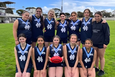 Un grupo de jóvenes deportistas posando en el campo de césped frente al estadio de deportes de la Hallett Cove School.