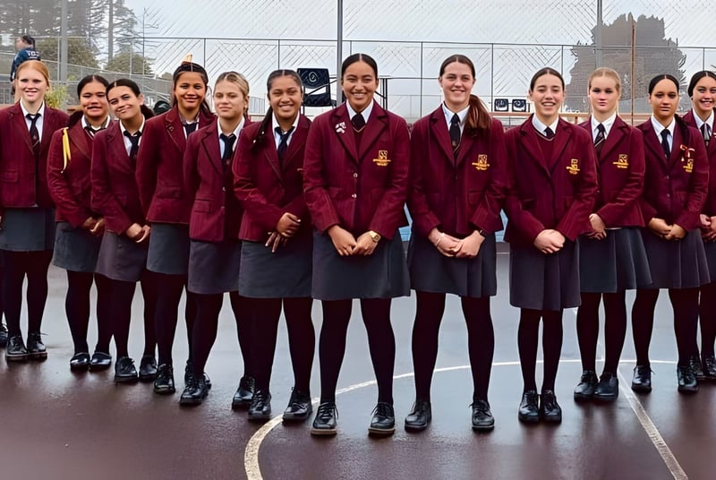 Un grupo de alumnas de la Hamilton Girl's High School está vestida con uniforme burdeos en el campus escolar al aire libre.