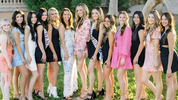 Un grupo de jóvenes mujeres en vestidos coloridos posan en el área verde del terreno de Hamilton High School.