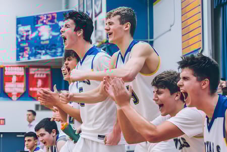 Un grupo de jugadores de baloncesto masculinos está en la cancha y aplaude en el campus de la Handsworth Secondary School.