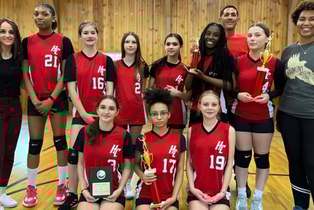 Un grupo de jóvenes atletas en camisetas rojas posan juntos en el gimnasio de la Harmony Christian School.