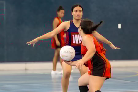 Dos alumnas de Hastings Girls' High School juegan al netball, una sostiene la pelota, la otra defiende.