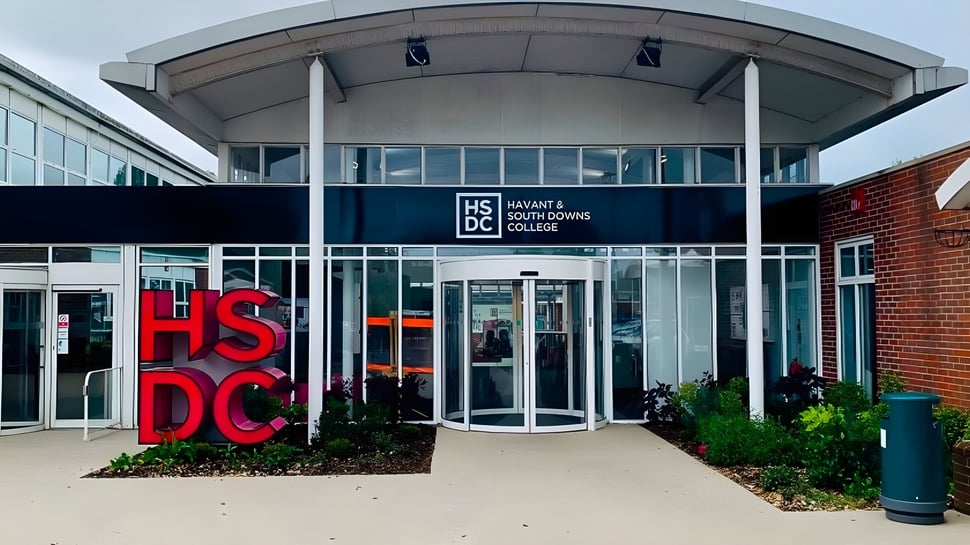 El moderno edificio de vidrio y ladrillo con grandes letras rojas HSDC en el campus del Havant College.