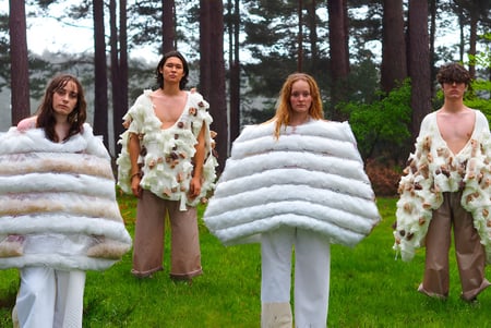 Cuatro modelos llevan en el terreno del Havant College llamativos atuendos blancos y beige en el bosque con altos pinos.