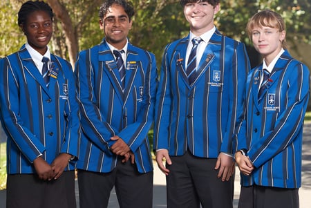 Un grupo de cuatro estudiantes de la Havelock North High School está de pie en un campo verde al aire libre.