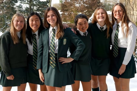 Un grupo de alumnas en uniforme escolar se encuentra en un paisaje invernal nevado en el campus del Havergal College.