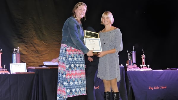 Dos personas están en el escenario de la Hay Lakes School sosteniendo juntos un premio.