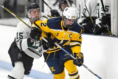 Dos jugadores de hockey de la H.B. Beal Secondary School luchan sobre el hielo por el puck.