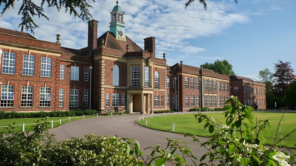 El histórico edificio de ladrillo con una alta torre en el campus de la Headington School está rodeado de un jardín bien cuidado.