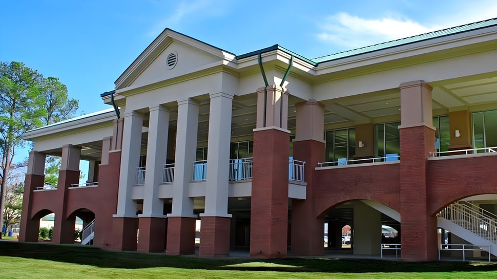 El edificio de ladrillo de varios pisos con entrada de columnas y techo verde se encuentra en el terreno de la Heathwood Hall Episcopal School.