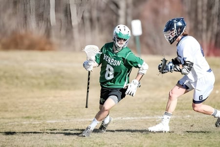Dos jugadoras en uniformes de lacrosse compiten entre sí en el campo de juego de la Hebron Academy.