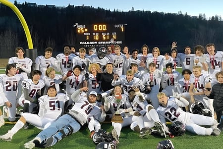 Un grupo de estudiantes juega al fútbol en el campo de la Henry Wise Wood High School con un marcador en el fondo.