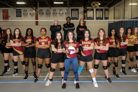 Las alumnas de la Heritage Christian Academy están juntas en una sala de deportes con sus uniformes de voleibol.
