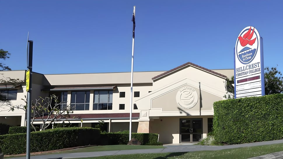 El moderno edificio de varios pisos de Hillcrest Christian College se encuentra en un entorno cuidado bajo un cielo despejado.