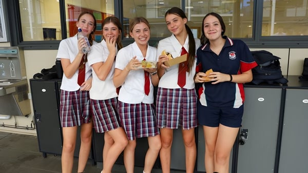 Un grupo de estudiantes en uniforme escolar está sonriendo juntos en el pasillo de Hillcrest Christian College.