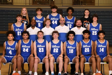 El equipo de baloncesto de la Hillcrest High School posa junto en camisetas azules en el gimnasio.