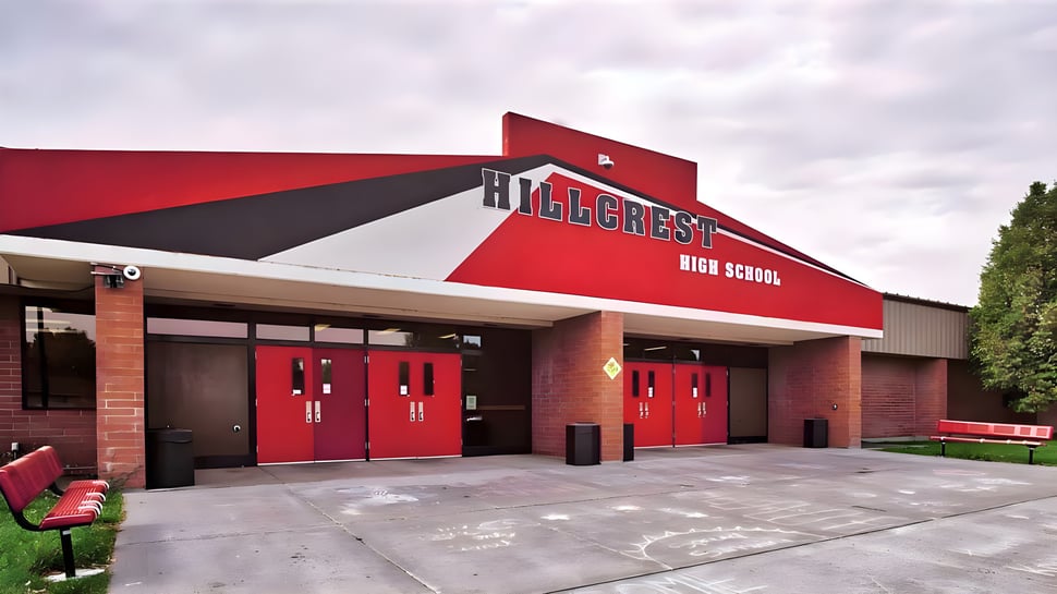 El edificio principal rojo y negro de la Hillcrest High School frente a un cielo nublado.
