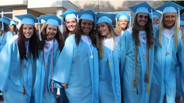 Un grupo de graduadas y graduados de la Holland Park State High School está en togas azules frente a un edificio celebrando su graduación.